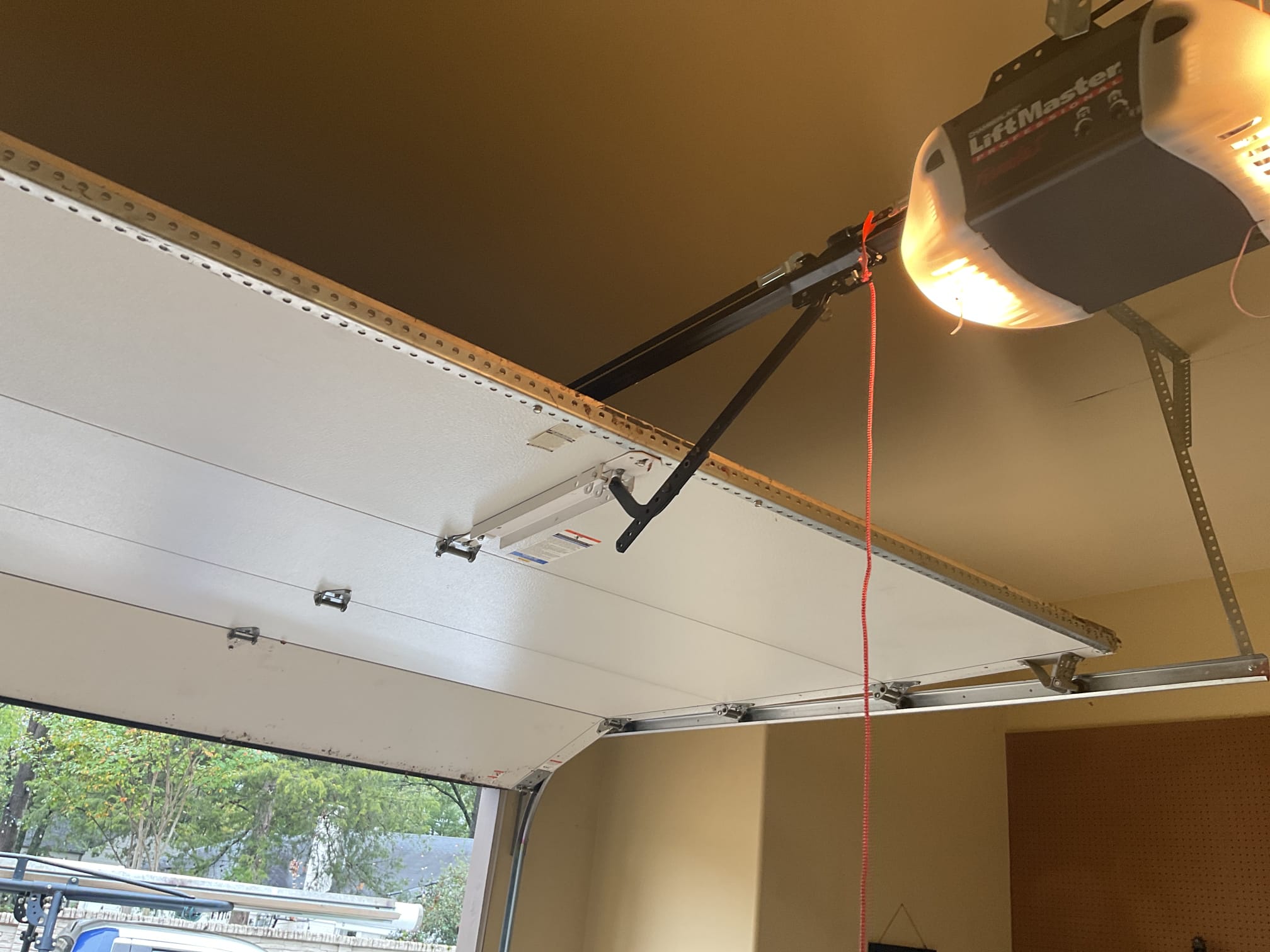 LiftMaster opener and rail positioned over an open garage door with the light turned on