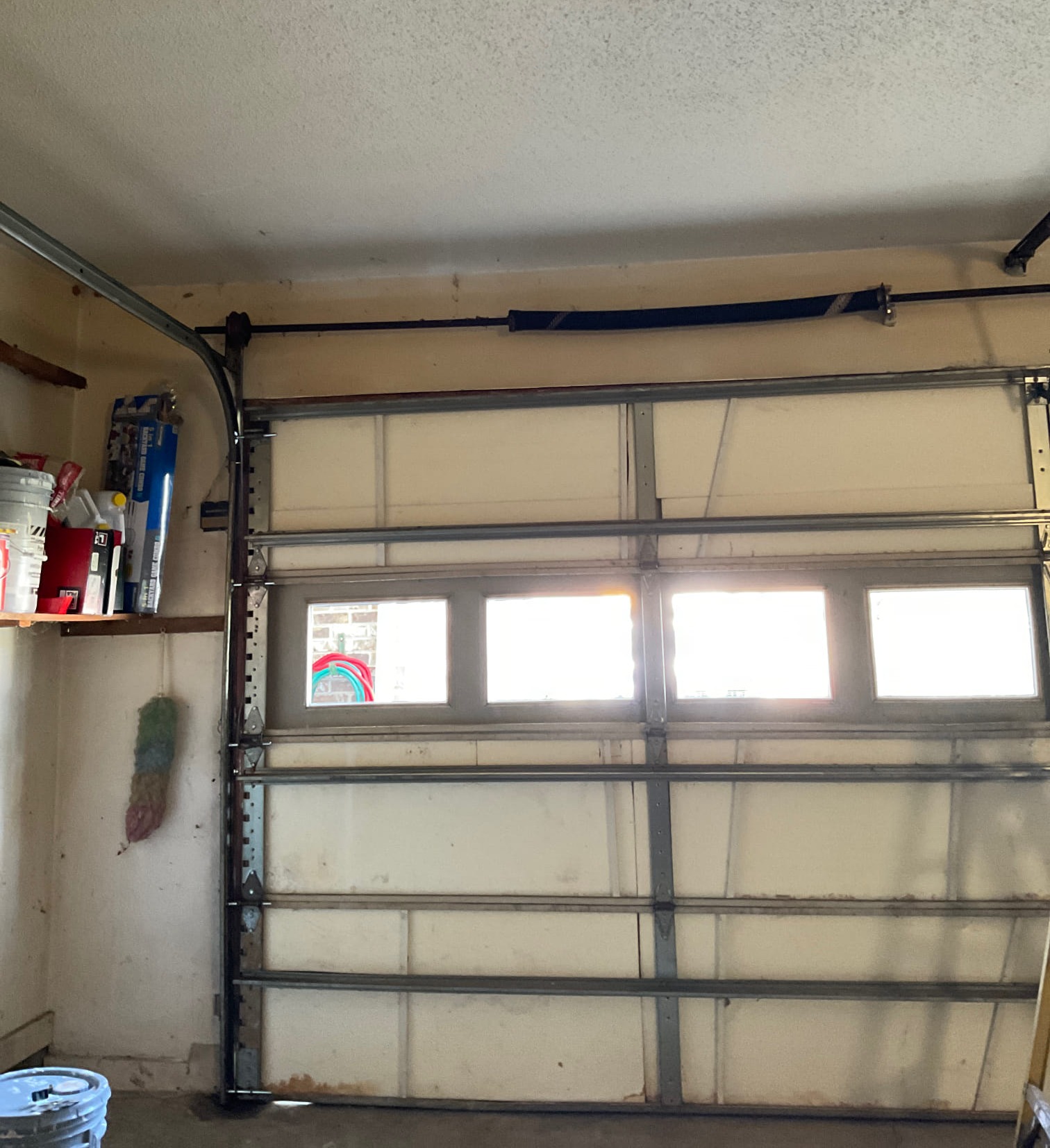 Interior view of a newly installed garage door with a row of windows letting daylight through